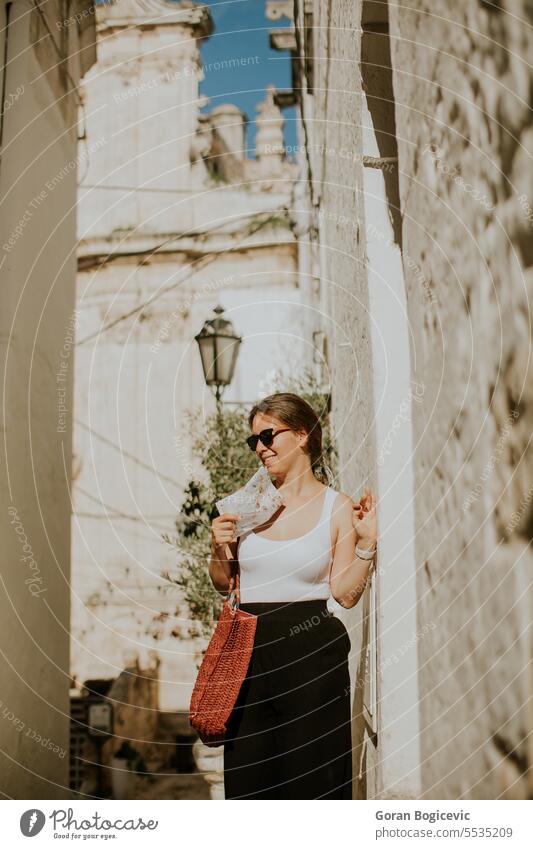 Female tourist with paper city map on narrow streets of Ostuni, Italy woman female tourist map direction navigation exterior tourism house building summer