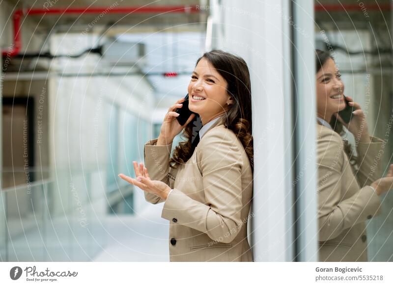 Young business woman using mobile phone in the office hallway caucasian professional businesswoman female people person confident talking cellphone