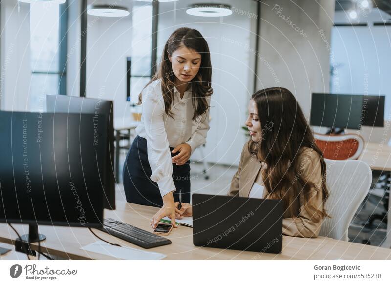 Young business women discussing in cubicle at the office adult brainstorming businessperson businesswoman caucasian colleague communication company computer