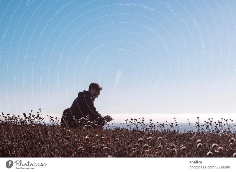 Man sitting down meditating in nature Nature Field Cliff Flower quiet quietness quiet scene quiet moment Calm calm atmosphere Meditation Meditative Prayer pray