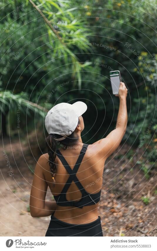 Female hiker taking selfie in forest woman smile break weekend travel smartphone female woods happy hat self portrait glad traveler tree nature mobile brunette