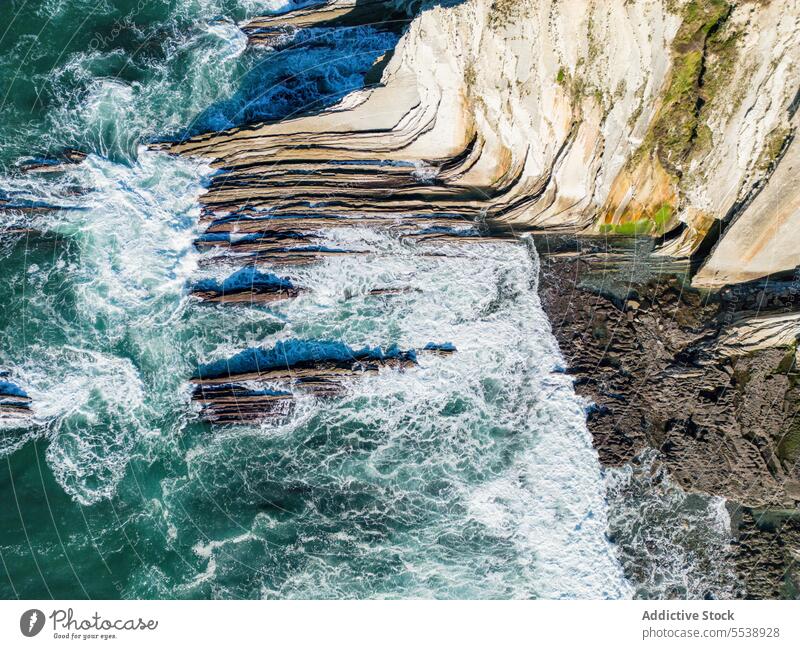 Rocky cliff against waving sea seascape coast seashore ocean rocky cloudless blue sky water tourism trip journey picturesque travel vacation basque harsh foam