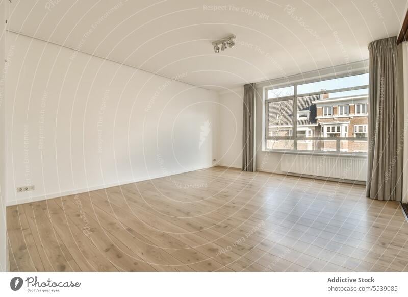 Empty living room with large window and white walls empty curtain bright copy space radiator hardwood floor daylight interior spacious house ceiling apartment