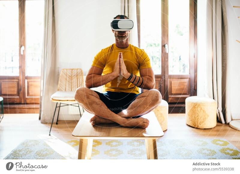 Man in VR headset exercising in light room man yoga lotus pose vr virtual reality practice meditate goggles male digital detox cyberspace mindfulness simulate