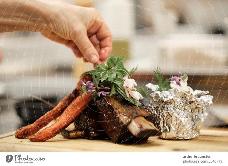 Roast rib of beef freshly prepared by the cook in the kitchen with wild herbs baked potato and carrots Cooking boil Kitchen kitchen herbs chef de cuisine