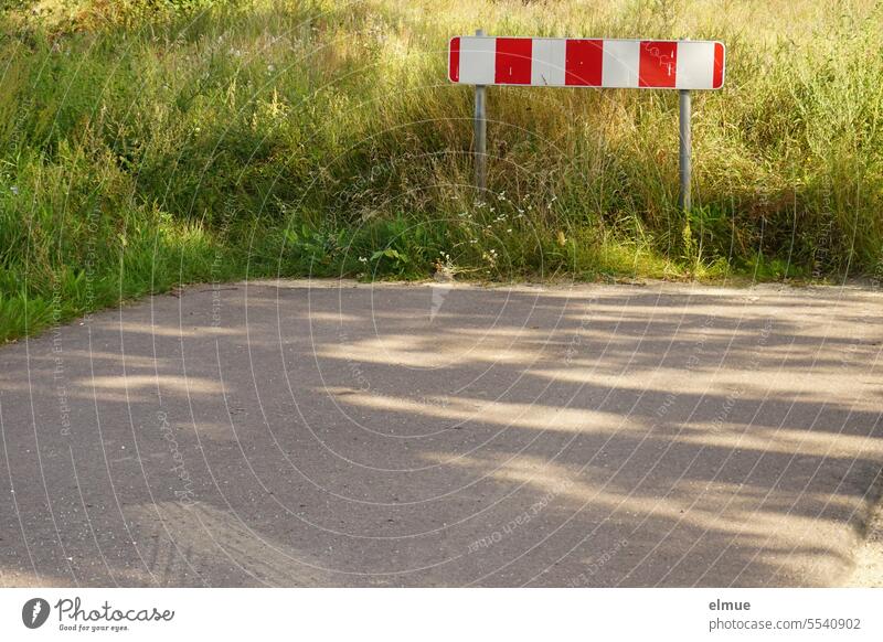 Red and white barrier at the end of a road in front of a meadow Reddish white demarcation Countdown marker barrier fence Protective Grating Guide beacons Grass