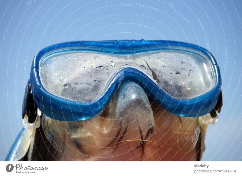 Boy with blue diving goggles and snorkel in front of blue sky in the sunshine on the beach of Sarimsakli near Ayvalik on the Aegean Sea in Balikesir province, Turkey