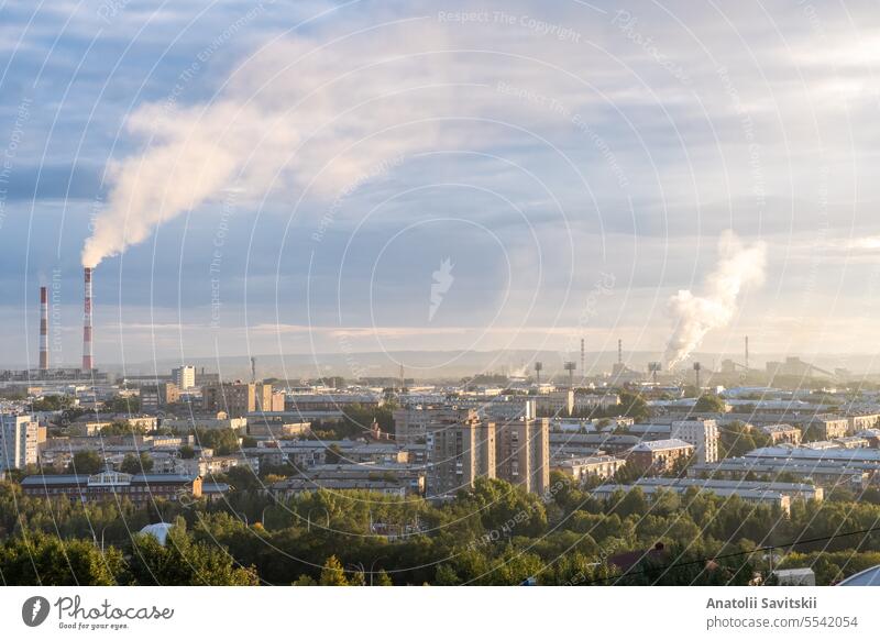 Beautiful urban area with houses and boiler room at sunset. View of the big city from above. Smoking chimneys of boiler rooms on the background of the cityscape