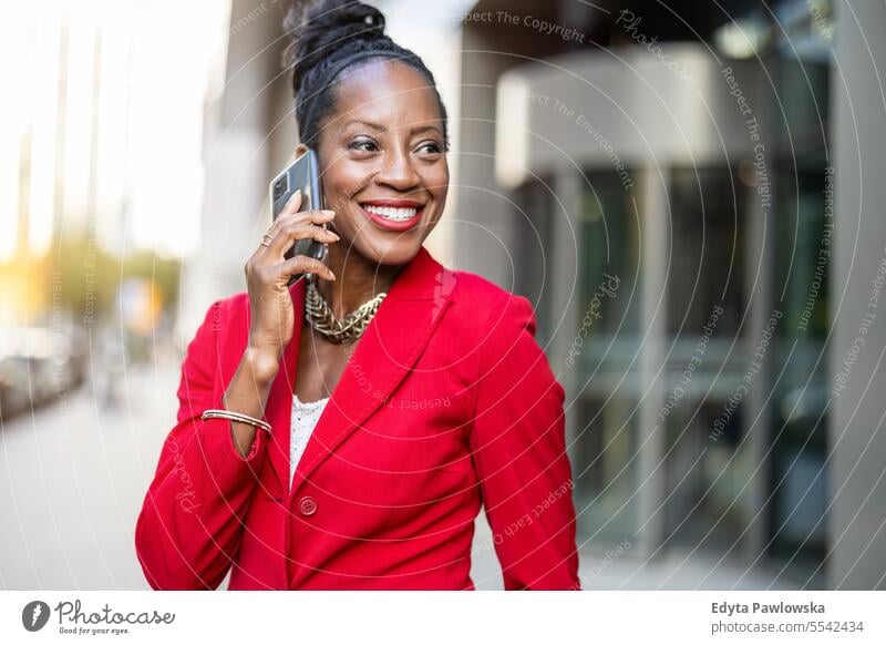 Portrait of smiling mature businesswoman using mobile phone in urban setting people downtown joy black natural attractive city black woman happiness street