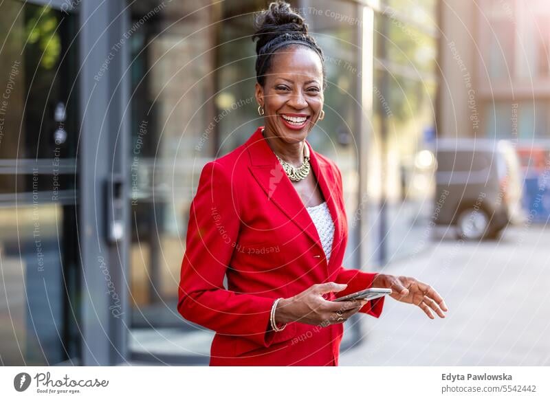 Portrait of smiling mature business woman using cell phone in urban environment people Downtown Businesswoman Joy Woman Black naturally Attractive City