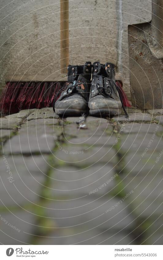 Worn-out work shoes with street broom and shovel on cobblestones house rules Assigned sweeping week Construction work labour Spade Broom Physical work Footwear