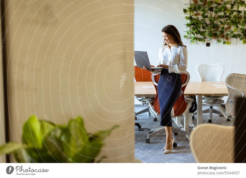 Young business woman with laptop in the office hallway adult businessman businesspeople businesswoman caucasian ethnicity communications computer corridor