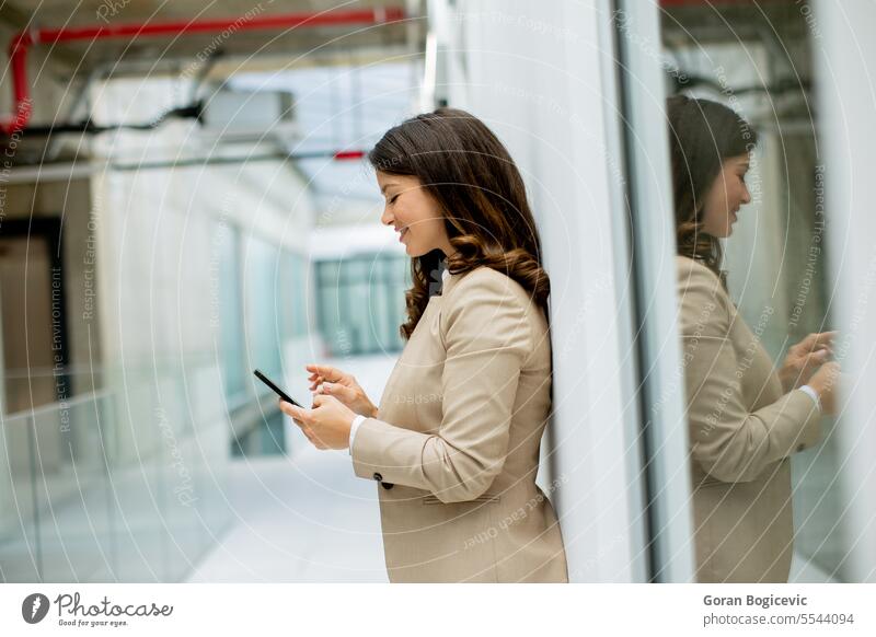 Young business woman using mobile phone in the office hallway caucasian professional businesswoman female people person confident talking cellphone