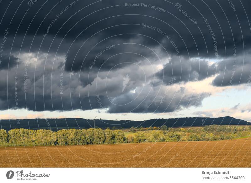 dramatic dark sky full of rain clouds over fields and trees in golden light rural cloudscape panorama weather landscapes sunlight road countryside magic shadow