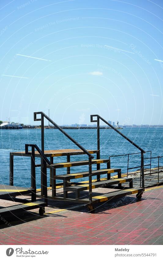 View through a glass pane of a movable makeshift staircase at the ferry dock across the Bosphorus in the Kadikoy district of Istanbul, Turkey, in summer sunshine