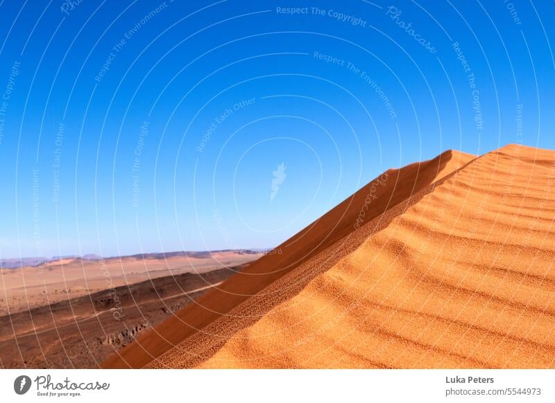 Red sand dune in Morocco desert in front of blue sky and wide landscape view. Desert duene Vacation & Travel Adventure Warmth Sand Africa Landscape