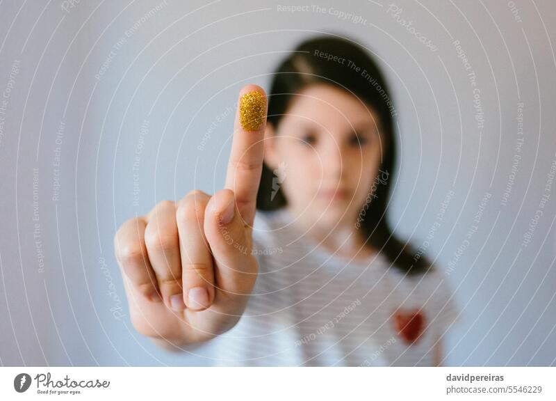 Serious young girl looks at camera and shows her finger covered with golden glitter Girl demonstrating Fingers Glitter microplasty Plastic Gesture Problem