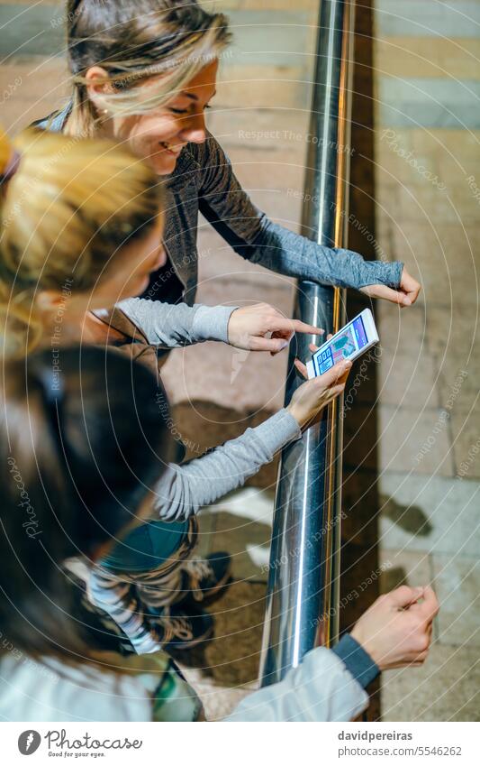 Top view of smiling women runners friends looking training route map on tracker cellphone app. smile circuit application mobile distance kilometer time happy