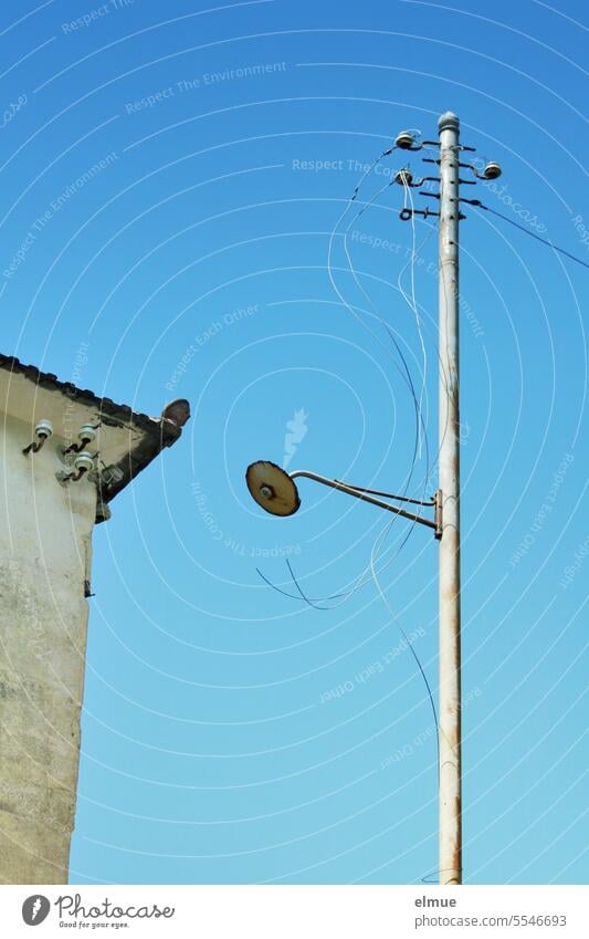 Old dilapidated street lamp with insulators and hanging power lines next to a house Insulator power supply Cable Transmission lines Electricity