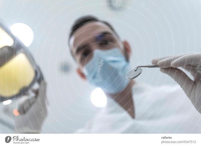 Low angle shot of a male dentist, doing the exam and checking up on oral health of the patient teeth cavity clinic clinical dental dentistry doctor examine