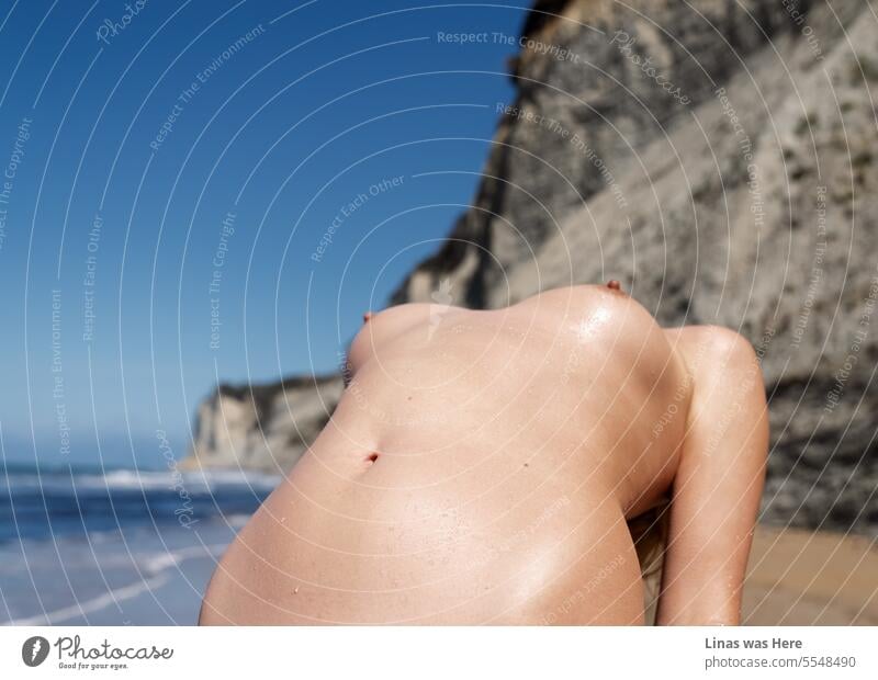 A gorgeous naked body of a pretty woman is in front of you. Her sexy curves in the scenery of rocky coastline, blue sky, and golden sand beach in Corfu, Greece. A lustful vacation is full of love.