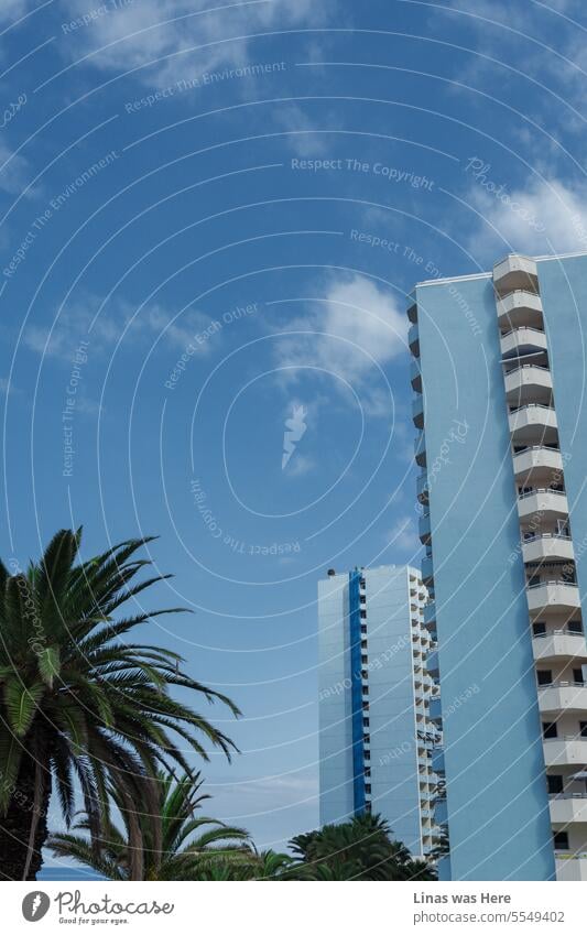 It's a perfect day in Tenerife, the Canary Islands. A blue-colored hotel is surrounded by a blue sky and the azure ocean waters, yet there's not a hint of blue mood, undoubtedly. It's a vacation postcard from Spain's island.