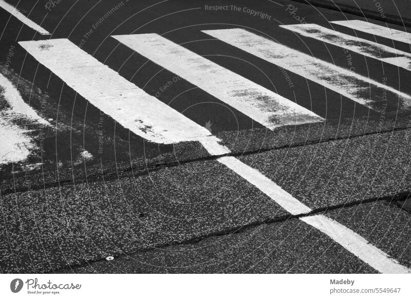 Crosswalk on repaired old gray asphalt in the province in Wettenberg Krofdorf-Gleiberg near Giessen in Hesse in classic black and white Pedestrian crossing