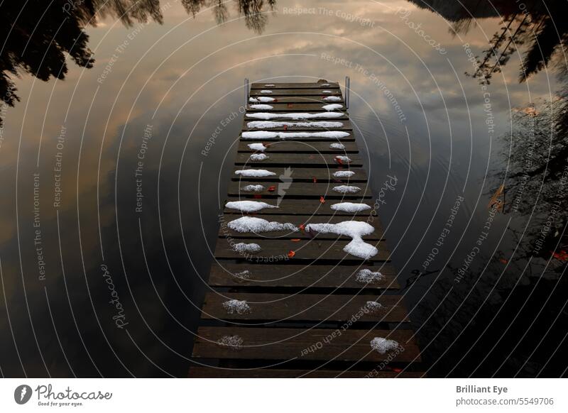 Snow-covered wooden jetty on a calm lake reflecting the evening sky Holiday season snow-covered Sky reflective chill Wood November Empty Peaceful Clouds