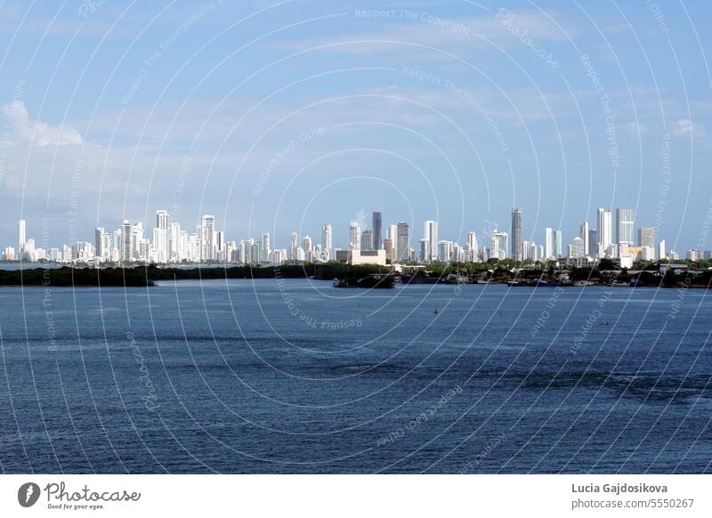 A distant silhouette of Cartegena, Colombia, with its tall modern buildings seen from the seaport on a sunny day. america apartment architecture background bay