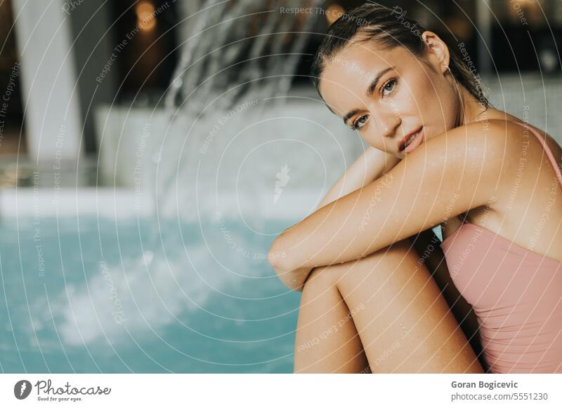 Young woman relaxing by the indoor swimming pool beauty wellbeing indoors poolside resting relaxation people water looking young adult freshness one person