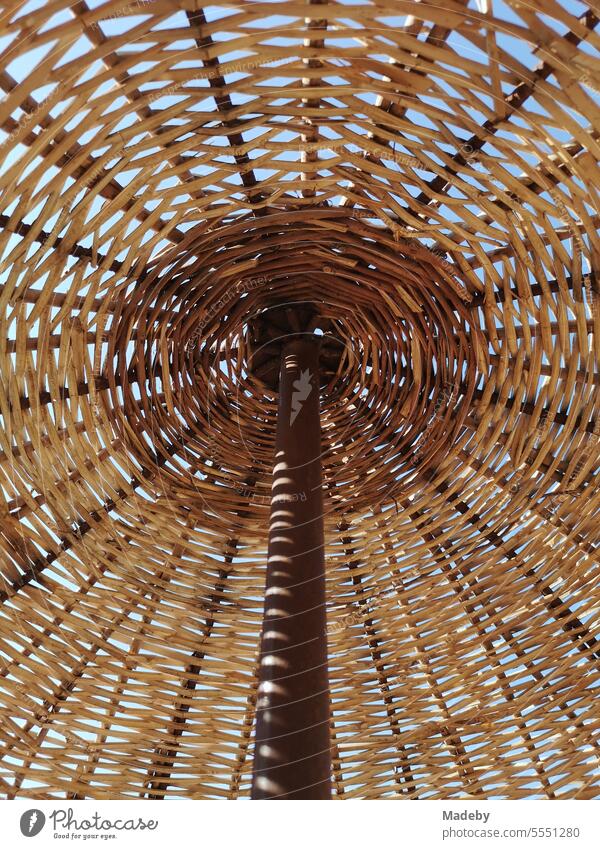 Large wicker parasol in beige and natural colors in summer sunshine on the beach of Ayvalik on the Aegean Sea in Balikesir province in Turkey Summer