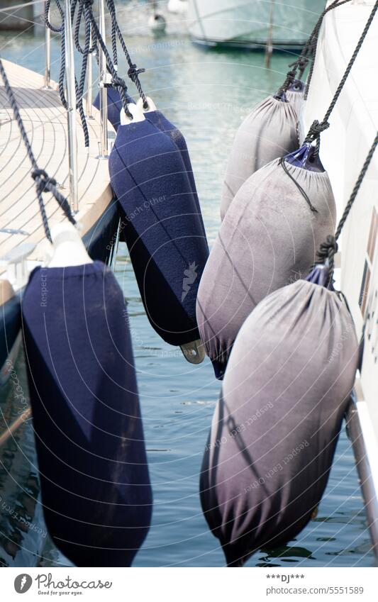 On the left side of the image are 4 buoys or fenders of a sailboat. On the right side are 3 buoys or fenders of a yacht. Fender deck ship Water Navigation Ocean