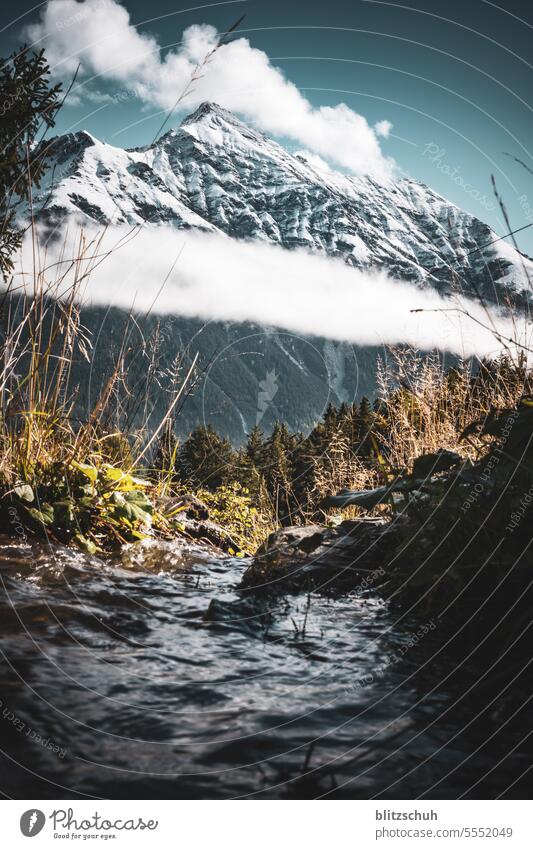 Snow-covered summit of the Lenzerhorn 2906m.a.s.l. with stream in the foreground Mountain Nature Tourism Landscape Vacation & Travel Alps Clouds Rock mountains