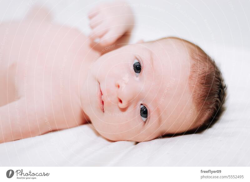 portrait of a newborn in studio lighting against white baby firstborn laying laying down copy space parenthood motherhood innocence life labor young boy happy