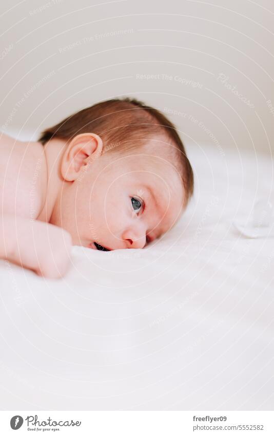 portrait of a newborn in studio lighting against white baby firstborn laying laying down copy space parenthood motherhood innocence life labor young boy happy