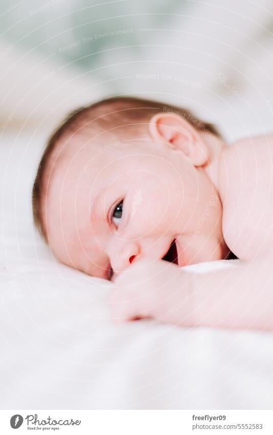 portrait of a newborn in studio lighting against white baby firstborn laying laying down copy space parenthood motherhood innocence life labor young boy happy