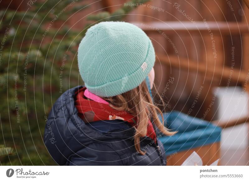 a child in winter clothes at the christmas market Child Winter Christmas Fair stalls Coniferous trees Cap winter jacket Cold Christmas & Advent Exterior shot