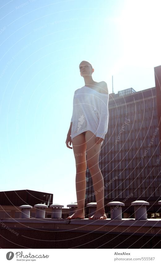 Young woman stands barefoot on a stone on a roof and looks around Youth (Young adults) Body 18 - 30 years Adults Cloudless sky House (Residential Structure)