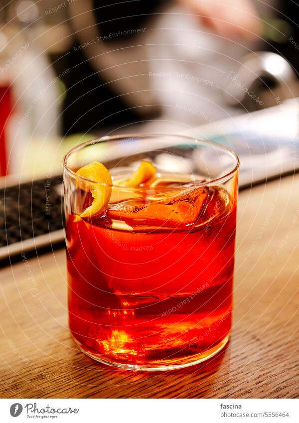 Negroni cocktail on bar counter. making bartender bartender cocktail barman orange drink boulevardier glass hand background table party restaurant ice red