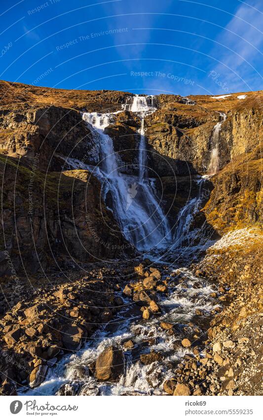 View of the waterfall Rjúkandafoss in the east of Iceland Waterfall River Island Landscape Nature mountain Rock Autumn Sky Clouds Blue Idyll vacation voyage