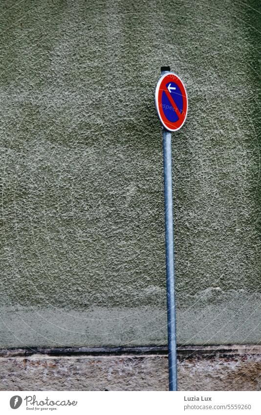 Restricted no stopping sign in front of a gray-green house wall, a play of colors Road sign limited holding ban restricted stopping sign Signs and labeling