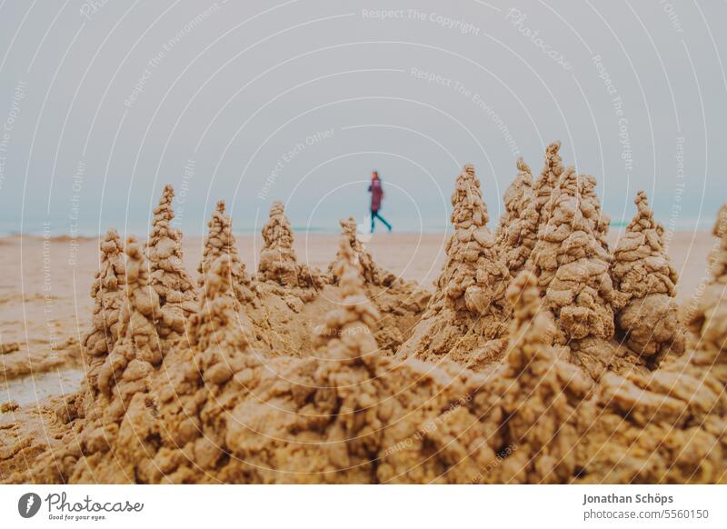 Beach walk behind sandcastle with towers on the beach in Warnemünde Walk on the beach Beach walkers Sandcastle protective wall vindicate rampart Autumn Ocean