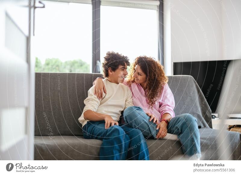 Happy mother and son sitting on sofa in living room at home real people adult apartment bonding boy child family female indoors kid lifestyle love mom