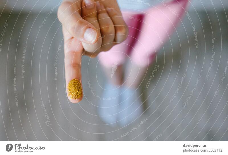 Unrecognizable child showing finger covered of golden glitter composed by harmful small plastics unrecognizable micro microplastics hand prohibition european