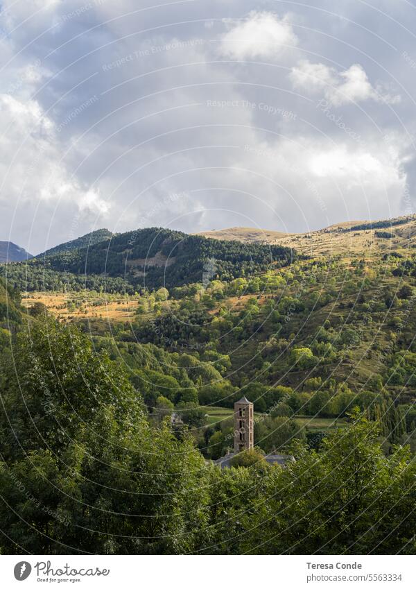 View of the tower of the church of Saint Climent in Taül (Lleida) among the autumn forest. Catalan Pyrenees. Spain. Romanesque church. landscape nature sky