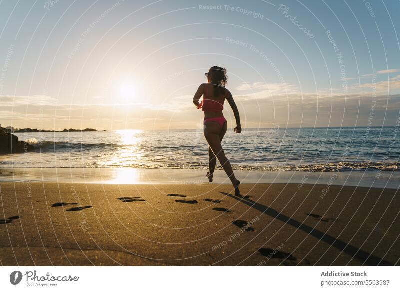 Happy woman running on sandy beach happy cheerful sea seaside barefoot summer carefree vacation bikini smile nature sun water positive enjoy travel pleasure