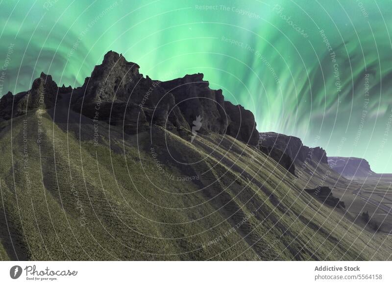 Majestic sky with northern lights over rocky cliffs mountain traveler nature cold aurora borealis range adventure highland landscape green admire formation