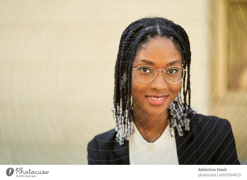 Smiling stylish African American woman standing against blurred background style businesswoman confident outfit building urban modern smile positive