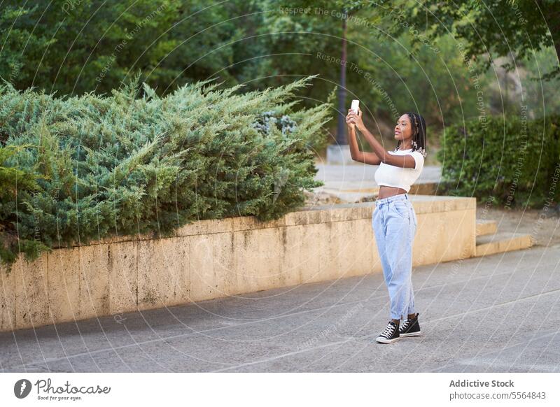 African American woman taking selfie on smartphone happy park take photo mobile using device tree cellphone moment bush social media memory self portrait stand