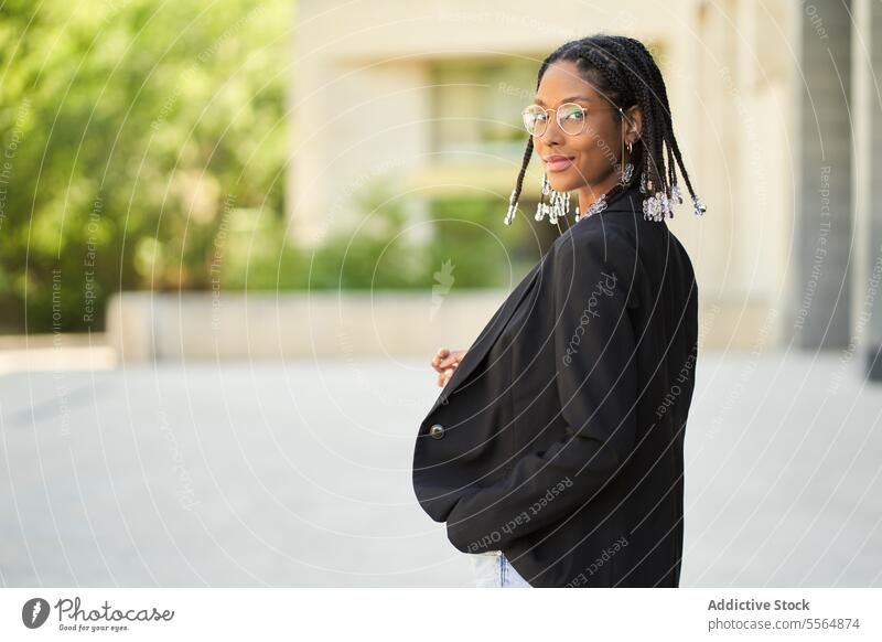 Smiling stylish African American woman standing against blurred background style businesswoman confident outfit building urban modern smile positive